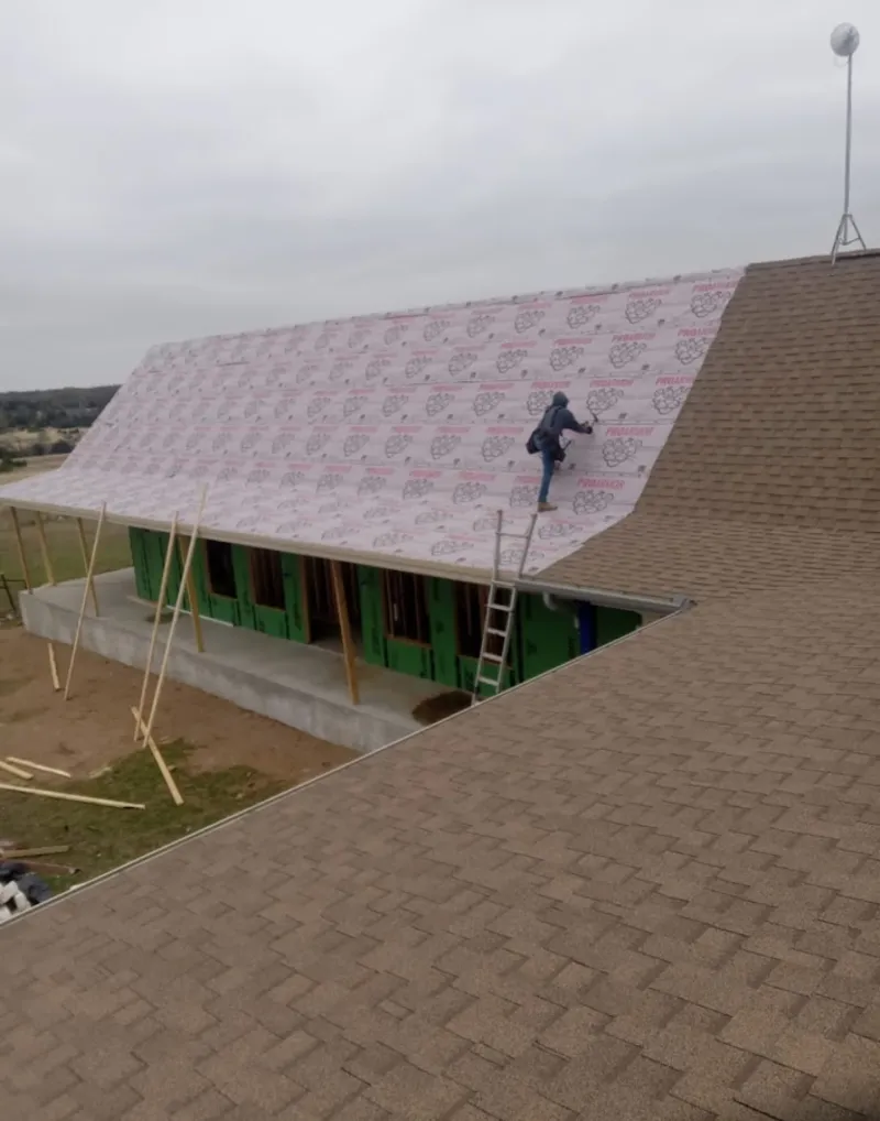 Worker preparing underlayment for a metal roof installation in Catalina